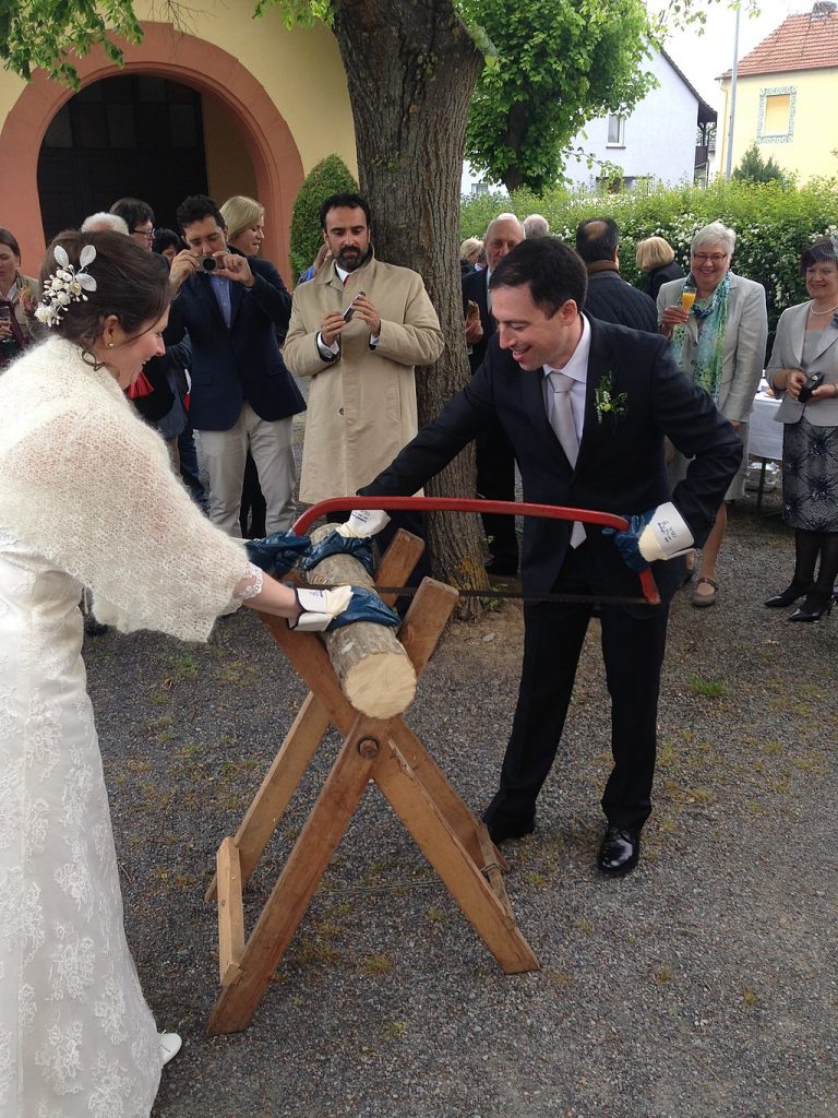 German wedding tradition of Baumstamm Sägen, where newlyweds saw through a log together as a metaphor for teamwork.